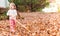 Happy toddler girl raking leaves