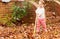 Happy toddler girl raking leaves