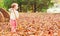 Happy toddler girl raking leaves