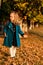 Happy toddler girl walking outdoors in autumn time. Fashion, autumn, childhood. Little girl wears trendy blue coat. Child plays