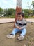 Happy Toddler playing with soil and dirt under a tree in a garden