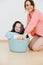 Happy toddler son sitting in laundry basin next to his mother