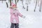 A happy toothless little girl playing with snow in the forest