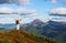 The happy tourist with the back pack stays on the hill. Autumn sunny day. Girl in sport clothes. Landscape of the mountains.