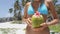Happy tourist bikini woman drinking fresh coconut water on beach vacation