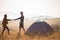 Happy tourist couple walk on top of mountains near tent and enjoy autumn morning in vacation.