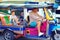 Happy tourist family having fun on traditional tuk-tuk taxi in asian city