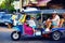 Happy tourist family having fun on traditional tuk-tuk taxi in asian city