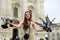 Happy tourist in front of Duomo cathedral, Milan, Milano. Funny girl with dove sitting between them. Doves eats feed