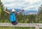 Happy tourist girl with raising hands and backpack sitting in the Austrian Alps mountain and enjoying summer and nature.