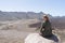 Happy tourist sitting in a rock of a viewpoint,with observation and relax in a volcanic desert