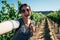 Happy tourist in sunny grape field taking selfie