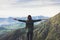 Happy tourist traveler standing on a rock with raised hands, hiker looking to a valley below in trip in spain, hipster young girl