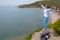 Happy tourist woman climbed to the top of the mountain. Emotions of joy and happiness. Mountain and sea in the background