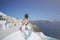 Happy tourist woman in flora dress at private pool villa, whitewashed village in Oia, Santorini Greece. mediterranean sea