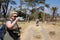 Happy tourist woman takes a selfie with zebras in the background while on a walking safari - Lake Naivasha National Park Kenya
