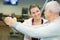 Happy trainer assisting senior man to exercise in gym