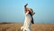 Happy travel female in white shirt rising hand enjoying freedom surrounded by wheat field