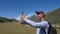 Happy traveler shooting video or photo panorama of valley on phone