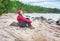 Happy traveler trekking woman sitting on the coast of sea