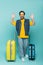 Happy traveler waving hands near suitcases