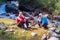 Happy travelers sitting by a river in the mountains