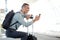 Happy traveling businessman looking at mobile phone at station