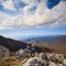 Happy traveller stands at the top of rock on scenic mountain lan