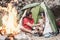 Happy trekker couple camping tent with dog next bonfire - Hipster man and woman having fun mountaineering together