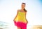 Happy trendy woman in colorful dress on seashore in evening