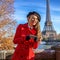 Happy trendy woman on embankment in Paris, France writing sms