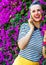 Happy trendy woman near flowers bed talking on cell phone