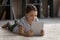 Happy tween girl child lying on carpet using digital touchpad