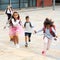 Happy tween schoolchildren with backpacks running to school outdoors