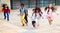 Happy tween schoolchildren with backpacks running to school outdoors