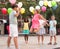 Happy tweenagers with balloons playing chinese jump rope in yard