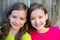 Happy twin sisters smiling on wood backyard fence