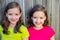 Happy twin sisters smiling on wood backyard fence