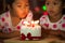 Happy twin two asian little girls blowing candles on birthday cake