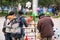 Happy two chinese mothers with babies choosing toys at the stall of senior male street vendor. Nansa public garden, Yunnan, South