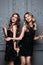 Happy two girlfriends in elegant evening black dress holding champagne glass, celebrate a holiday