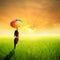 Happy umbrella woman jumping in green rice field and sunset