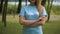 Happy unrecognizable Caucasian woman standing with crossed hands in summer park. Young female volunteer posing on clear