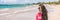 Happy vacation tourist woman relaxing on Puerto Rico beach banner panorama. Smiling young Asian girl in the sun, in