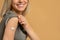 Happy vaccinated woman showing arm after vaccine injection, studio background, closeup