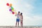 Happy Valentine day. Smiling couple hand holding balloon on the sand beach. Lover romantic and relax Summer,