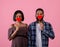 Happy Valentine's Day. Passionate black couple covering their mouths with red hearts on pink studio background
