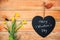 Happy valentine`s day written on a chalkboard in the shape of a heart, daffodils and wood planks background