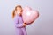 Happy valentines day heart. Baby girl presses to her chest pink inflatable heart on a light purple background