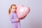 Happy valentines day heart. Baby girl presses to her chest pink inflatable heart on a light purple background